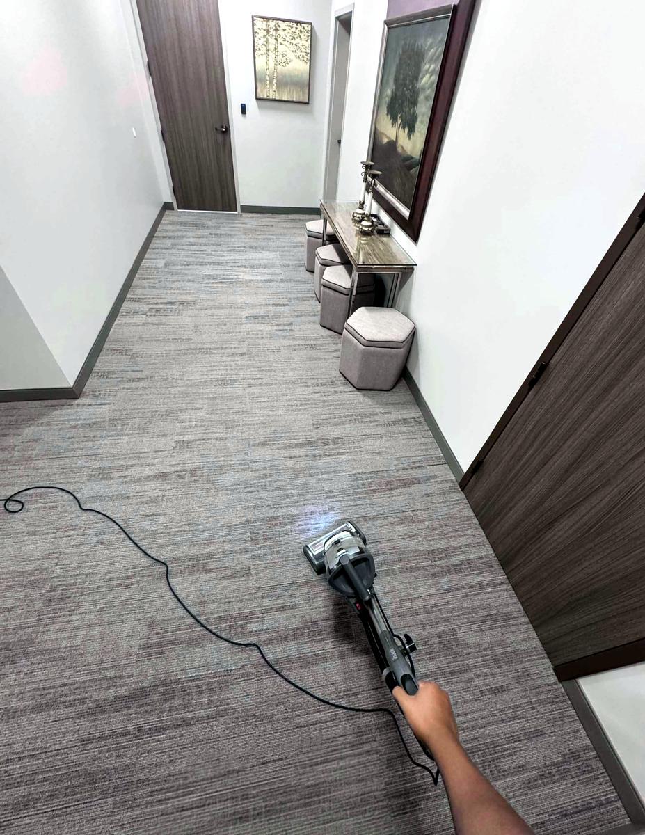 A crew member vacuuming an office hallway