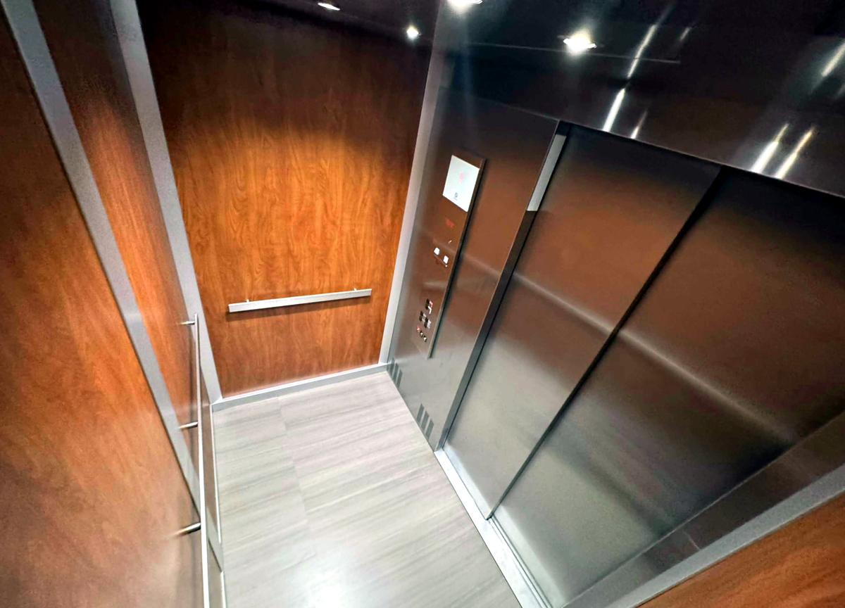 A spotless elevator with polished steel doors and wood panels