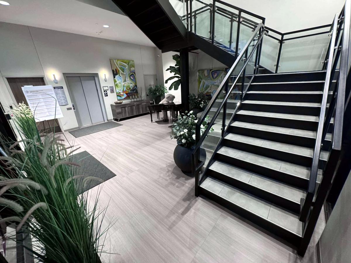 A clean office lobby with a staircase, plants and polished floors